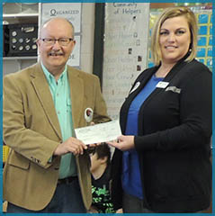 Carrie Burr presents a check to the Alpena News for Newspapers in Education